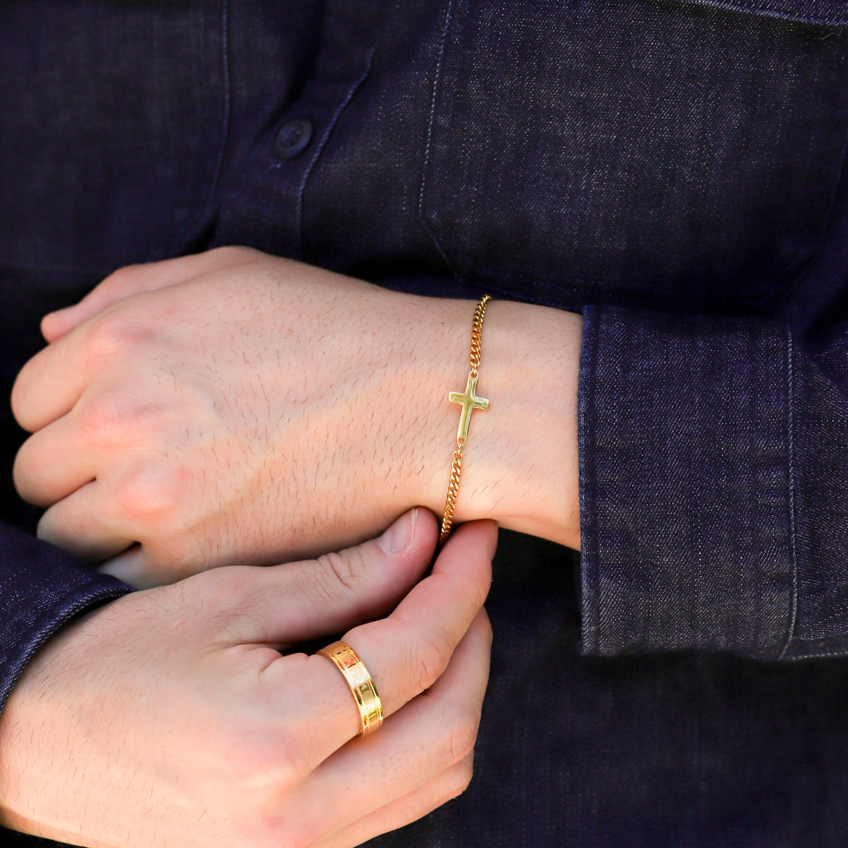 Gold cross bracelet on wrist with small cross charm and curb chain links