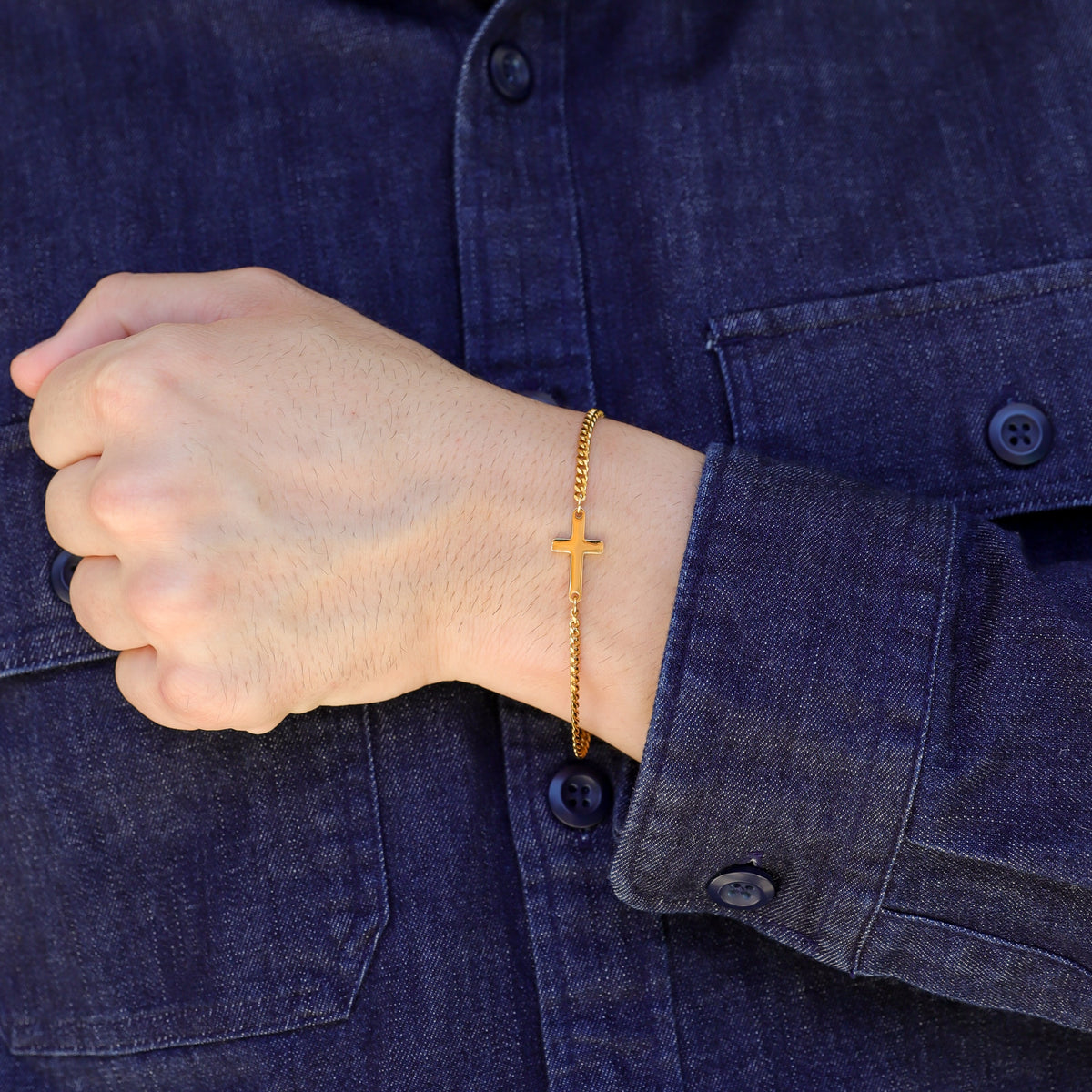 Gold cross bracelet on wrist with link chain and centered cross charm
