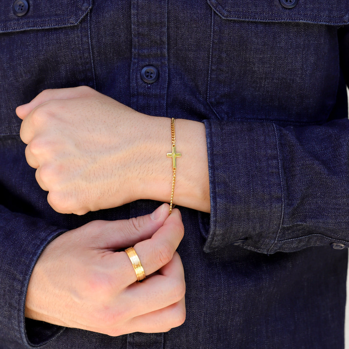 Gold cross bracelet on wrist with small cross charm on linked chain
