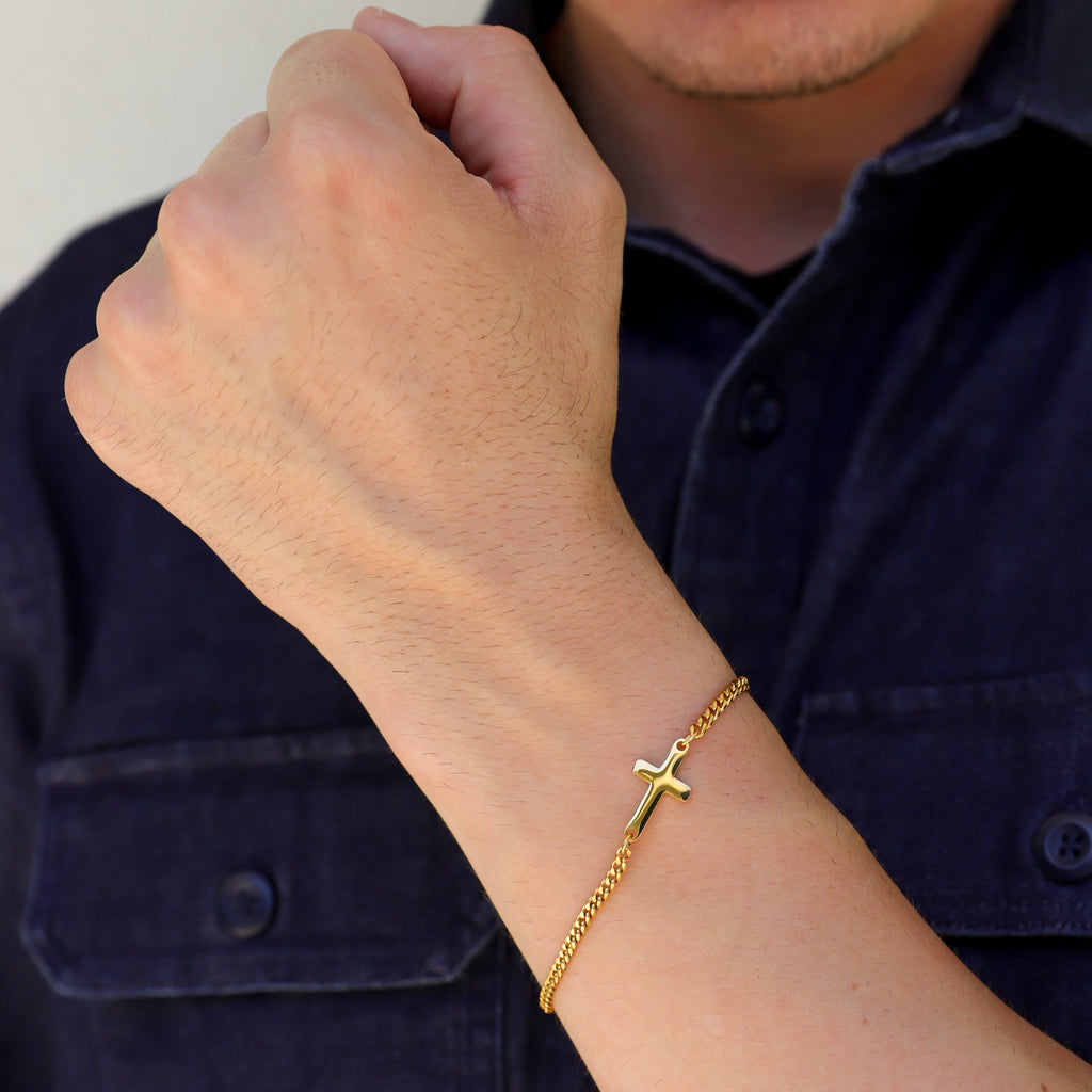 Gold cross bracelet on wrist showing small cross charm on chain links