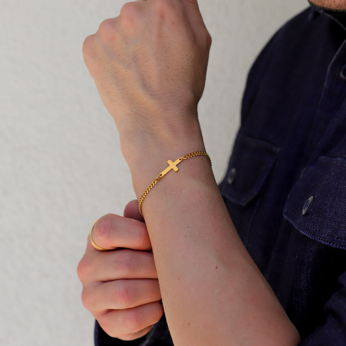Gold cross bracelet on wrist with small cross charm and linked chain