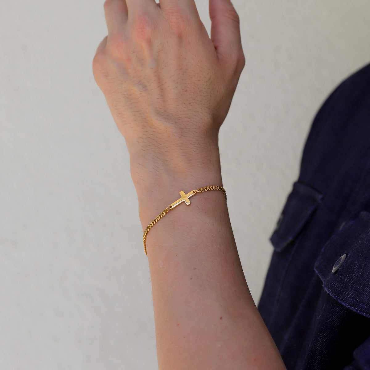 Gold cross bracelet on forearm with small cross charm and chain links