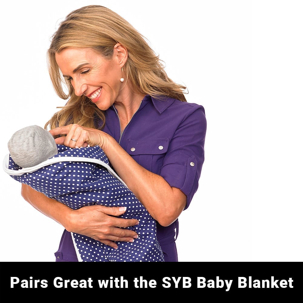 Gray infant beanie partially covered by navy polka-dot blanket