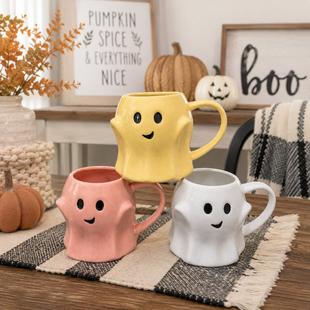 Ghost-shaped ceramic mugs in yellow, pink, and white with smile faces