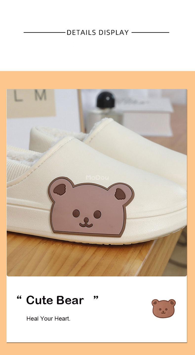 Cream slippers with bear patch, plush lining, and logo graphic