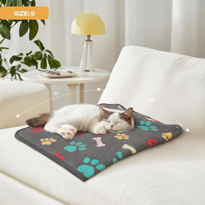 Pet blanket with colorful paw-print and bone pattern, laid on couch for a cat