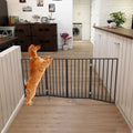 Freestanding folding pet gate with black vertical bars, blocking doorway in home.