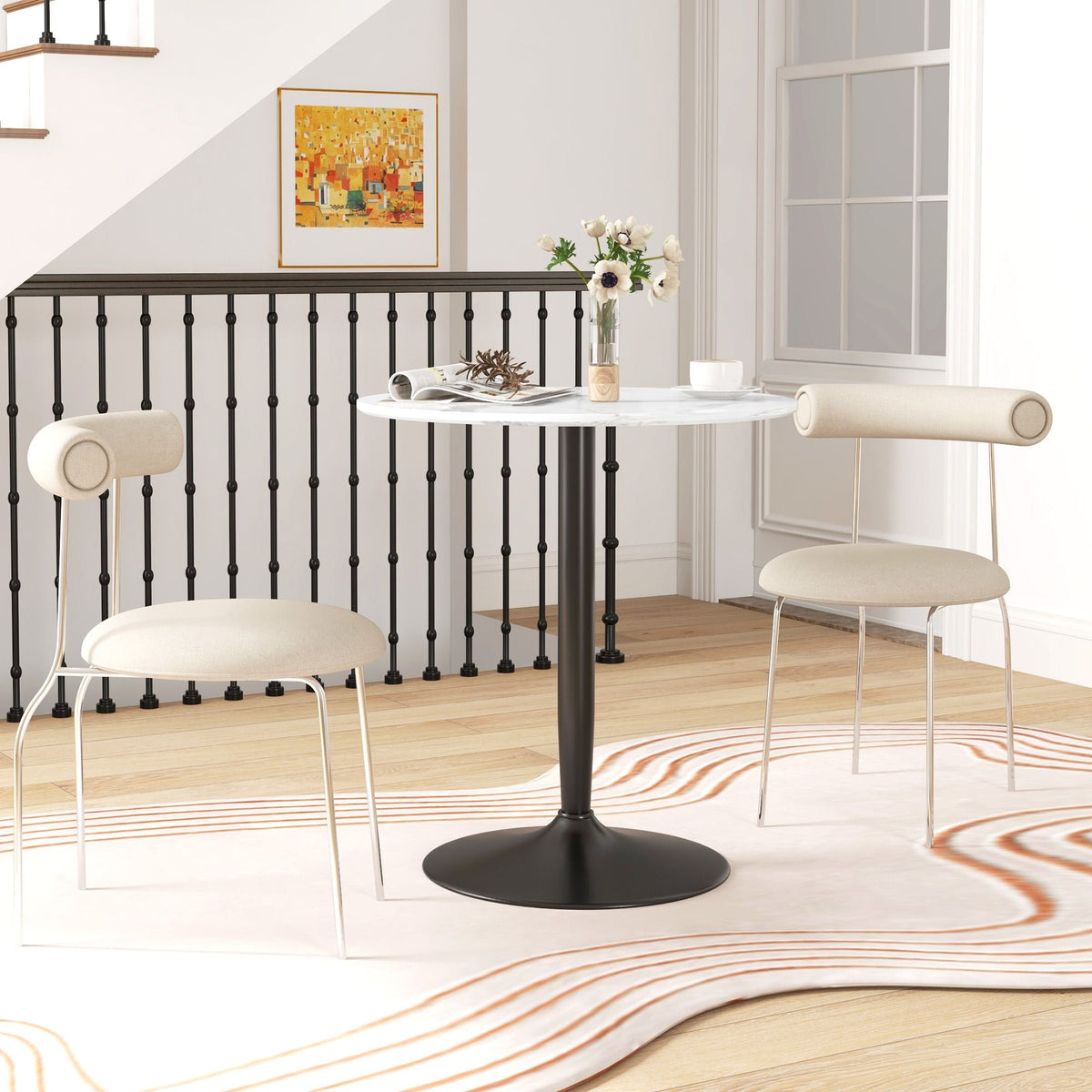 Round white marble dining table with black pedestal base in a bright room