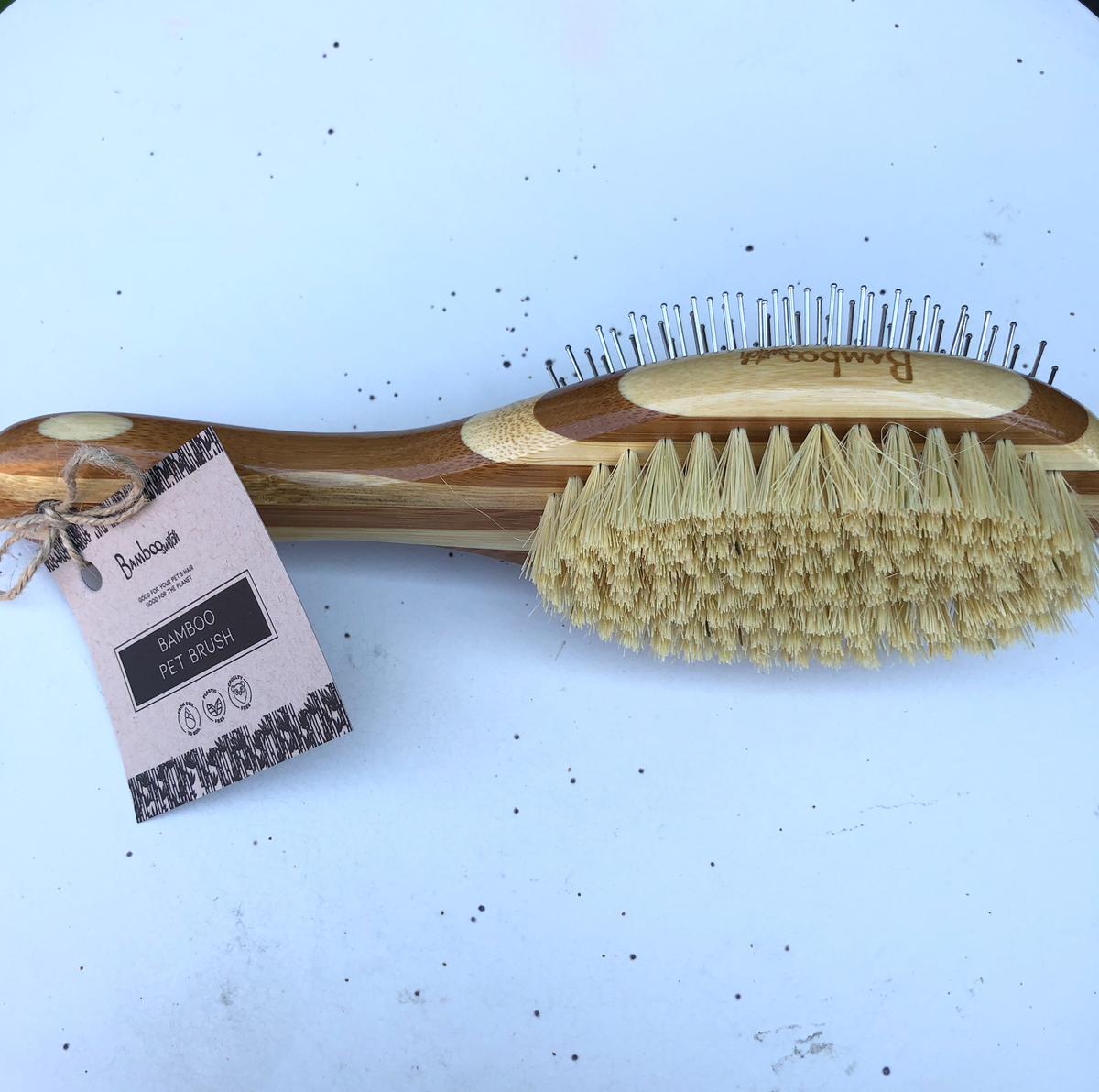 Bamboo grooming brush with oval wooden base and yellow stiff bristle pad