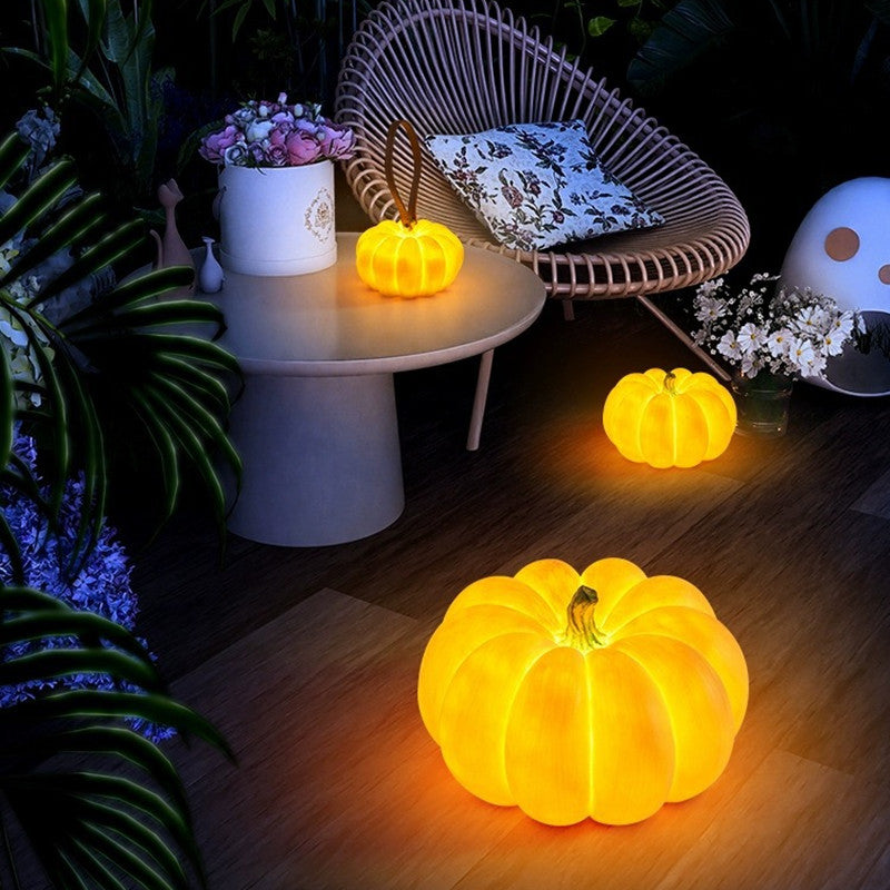 Glowing golden yellow pumpkin LED lights on patio table and floor