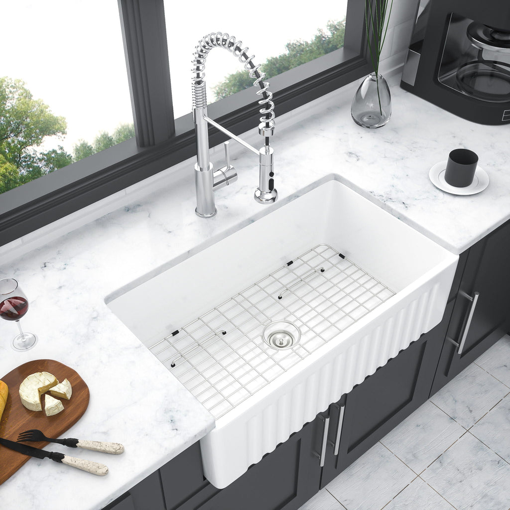 White single-bowl ceramic kitchen sink with wire rack and stainless drain strainer