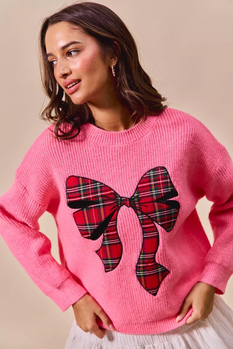 Pink crewneck sweater with plaid ribbon bow graphic and long sleeves