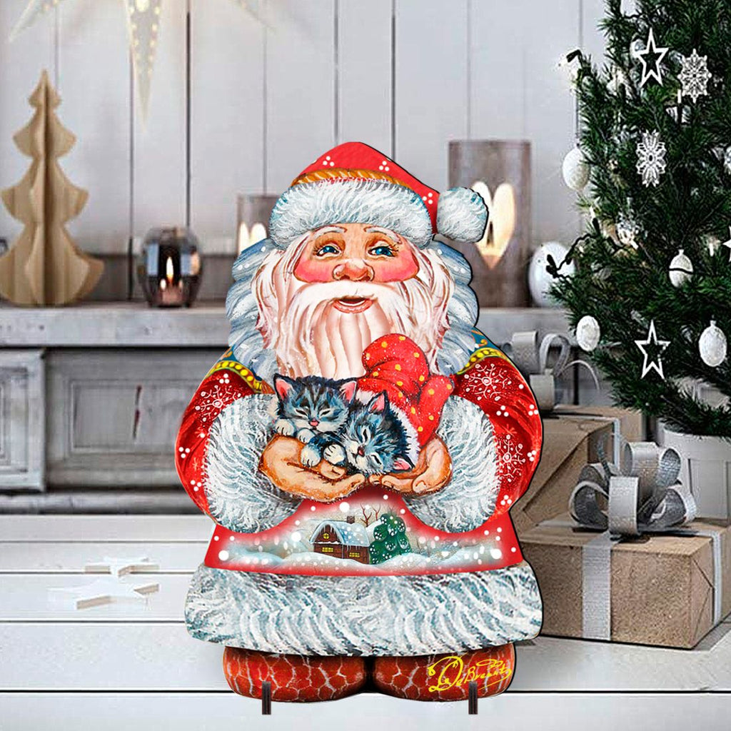 Santa holding a kitten yard sign in front of holiday decor, red hat and white beard