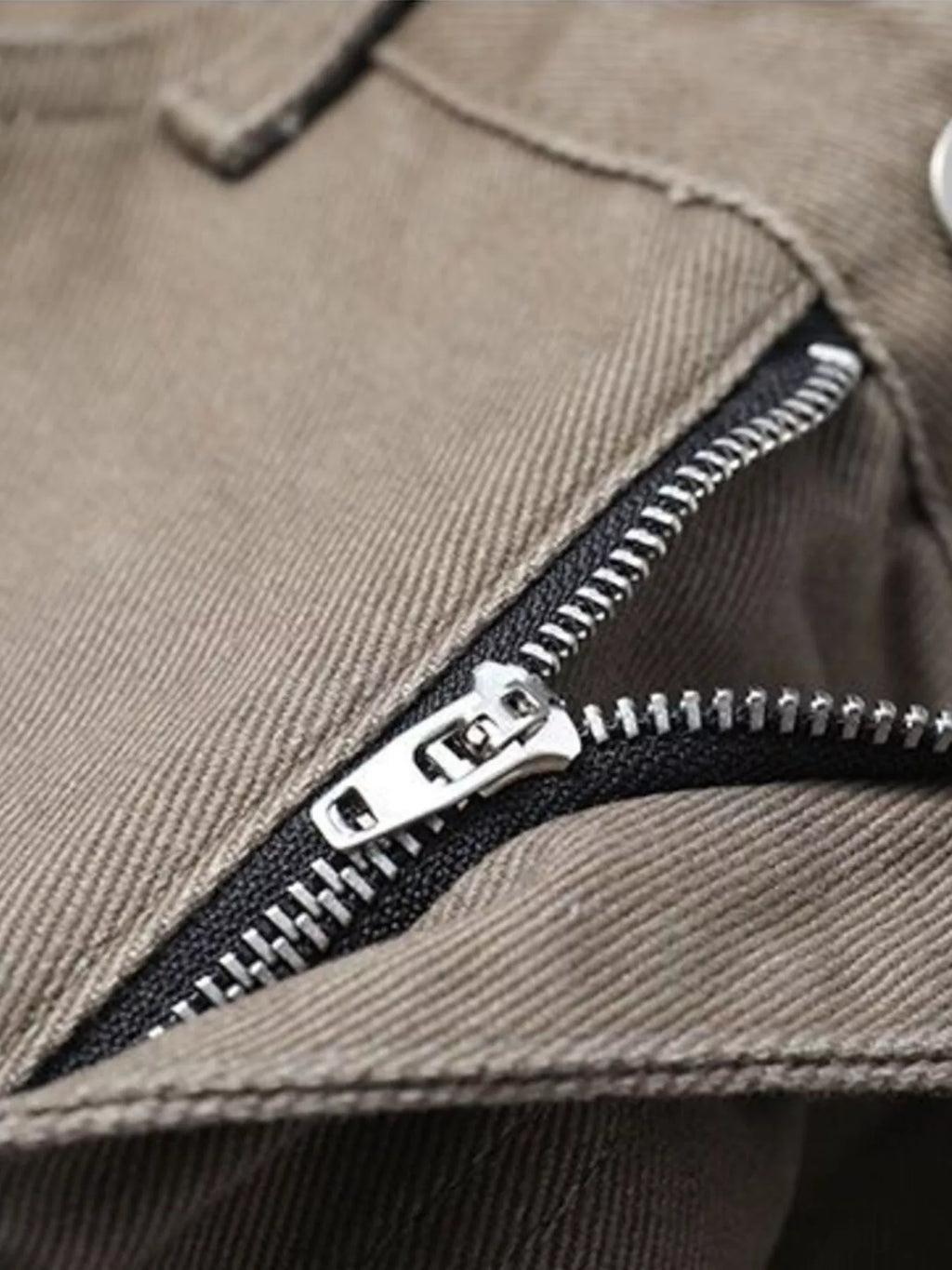 Brown pants zipper detail with metal pull and visible stitching