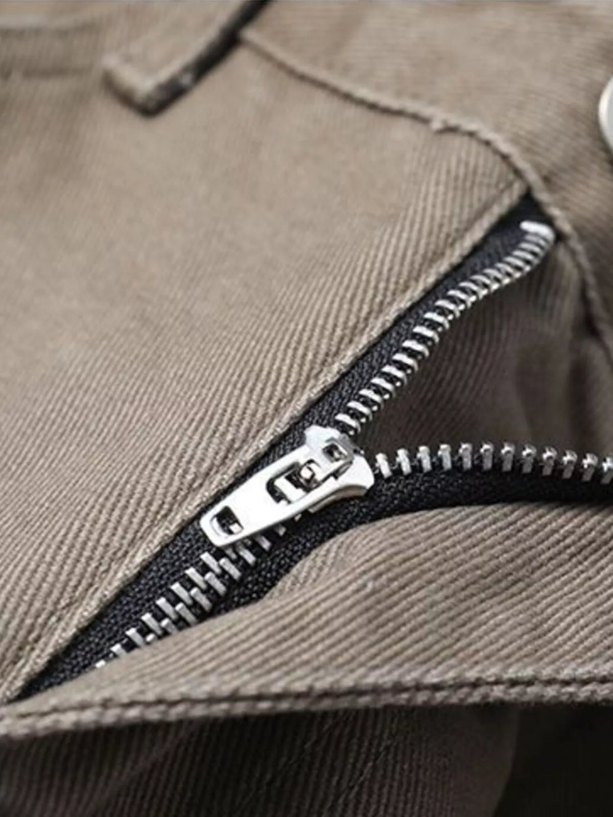 Brown pants zipper detail with metal pull and visible stitching