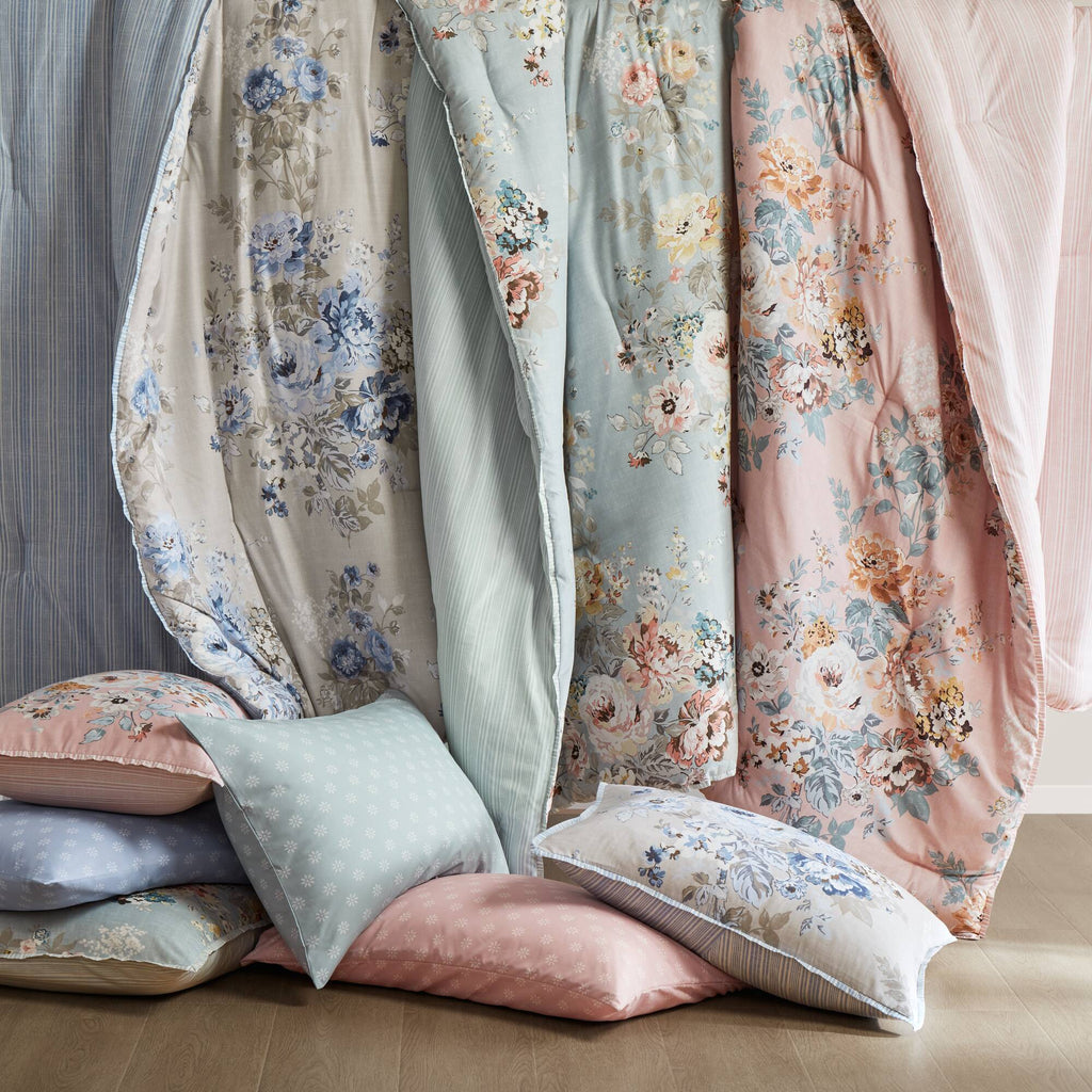 Light blue floral bedding layers with striped trim and matching pillowcases