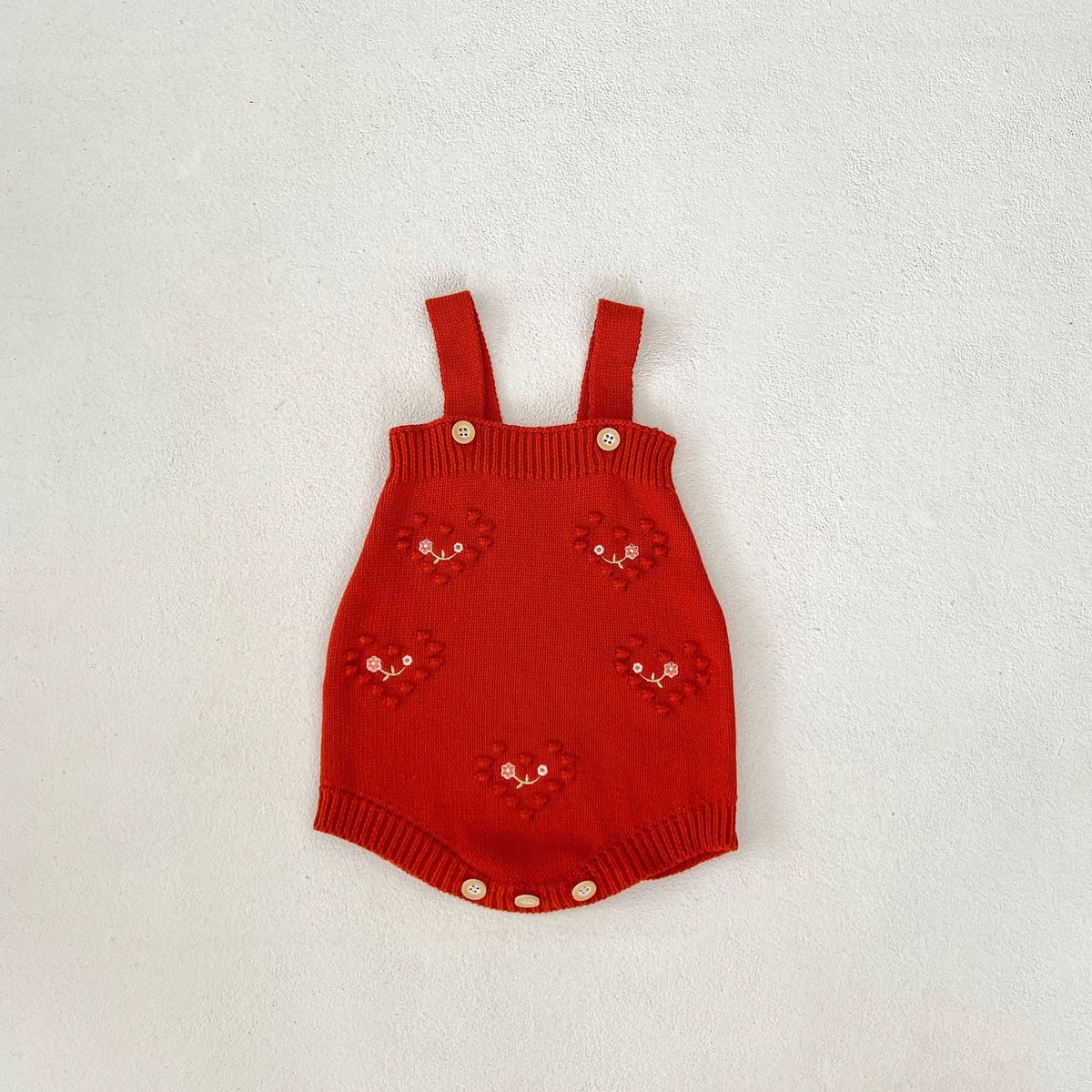 Red knit baby girl strap romper with embroidered heart motifs and snap bottom