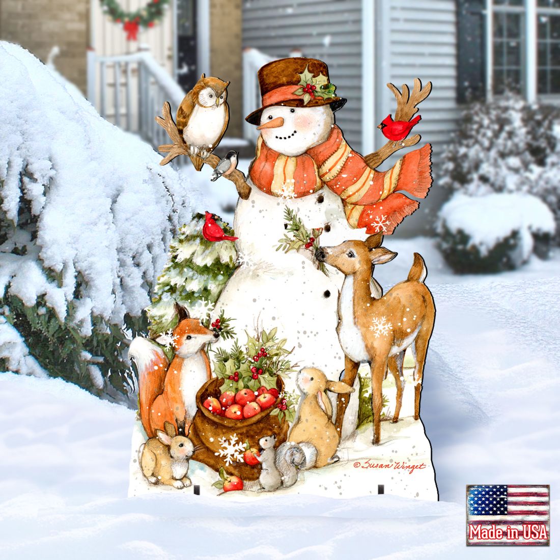 Outdoor yard sign with snowman, deer and rabbits, surrounded by evergreen tree and snow