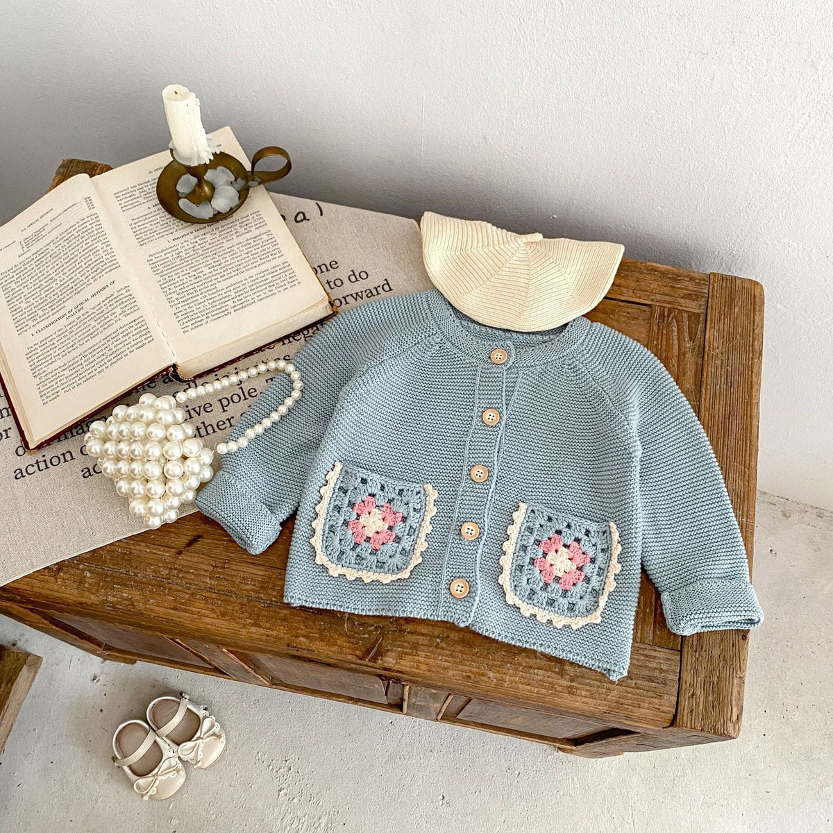 Smokey blue knit cardigan with round collar, button front, and crochet flower pocket squares