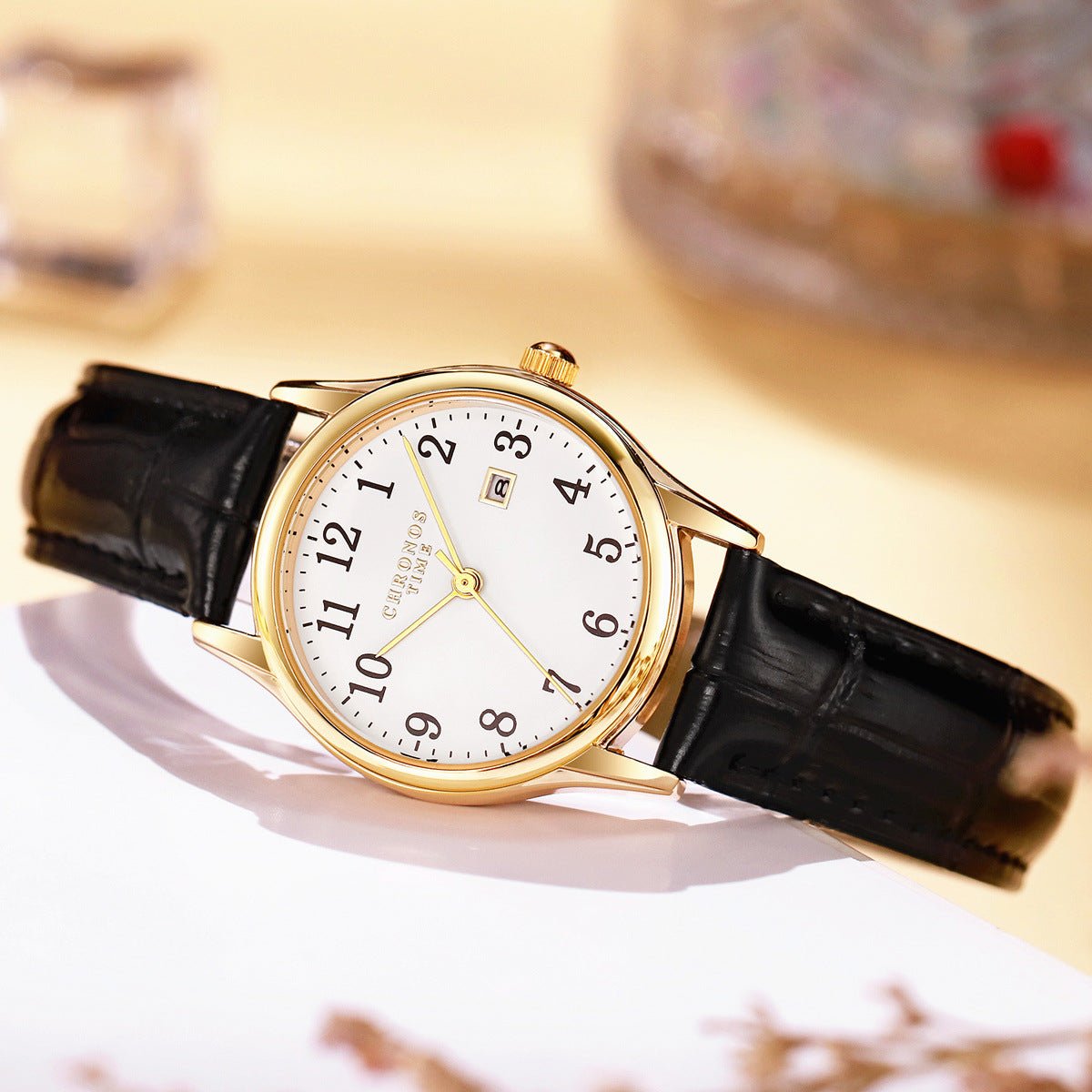 Minimalist digital-calendar wristwatch with white dial and brown leather strap, gold-tone case