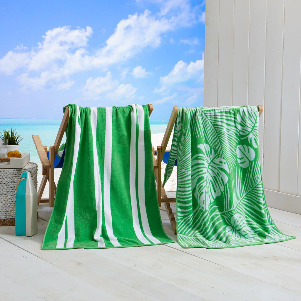 Green and white cotton velour beach towel on chair with palm leaf and stripe pattern