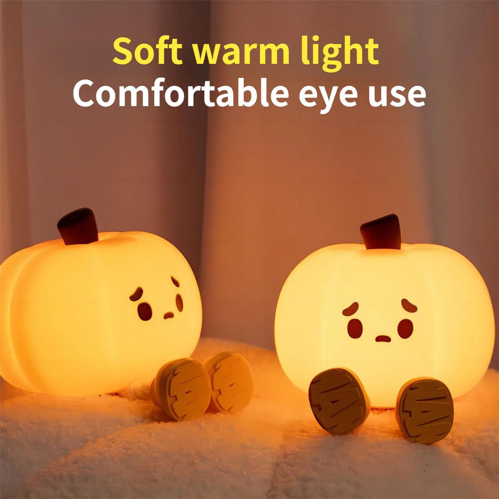 Two silicone pumpkin night lights with sad faces, warm soft light on bedding