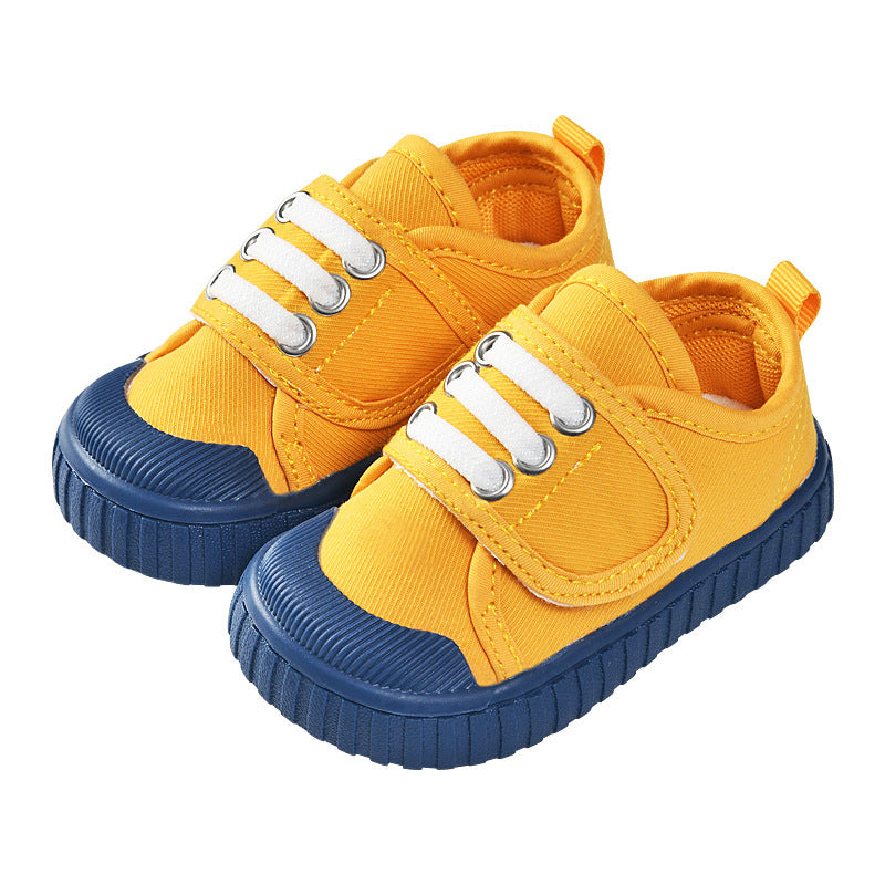 Yellow baby sneakers with blue sole, white lace eyelets, and hook strap