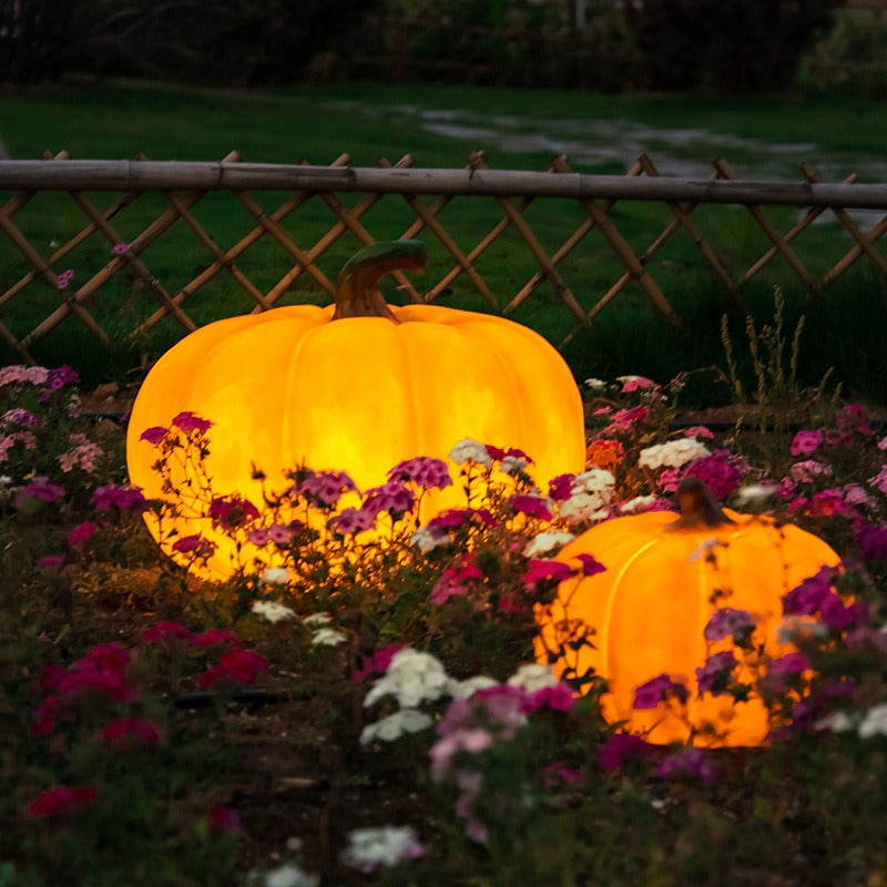 Glowing golden yellow pumpkin-shaped outdoor LED garden lights, two in scene