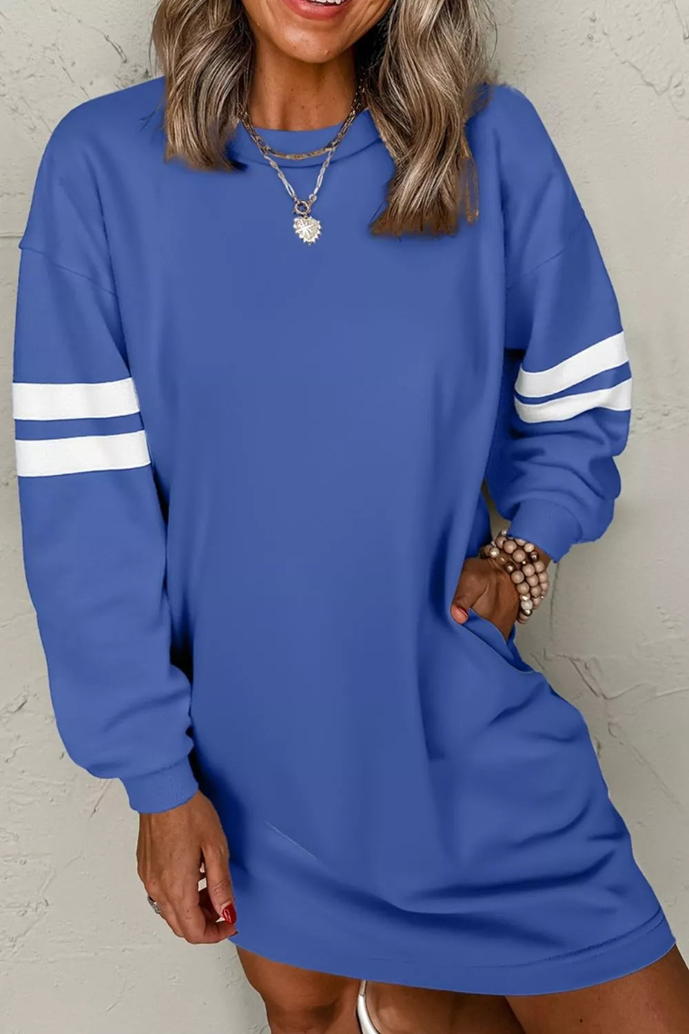 Dusty blue sweatshirt dress with white striped sleeves and round neckline, relaxed fit.