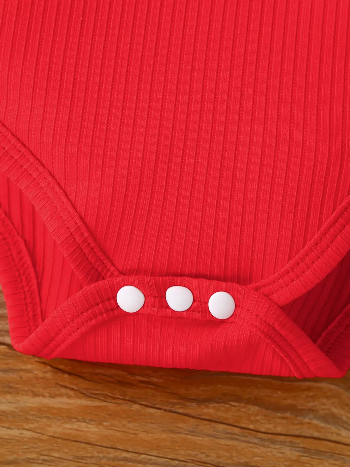 Red ribbed bodysuit with three white snap buttons at the bottom
