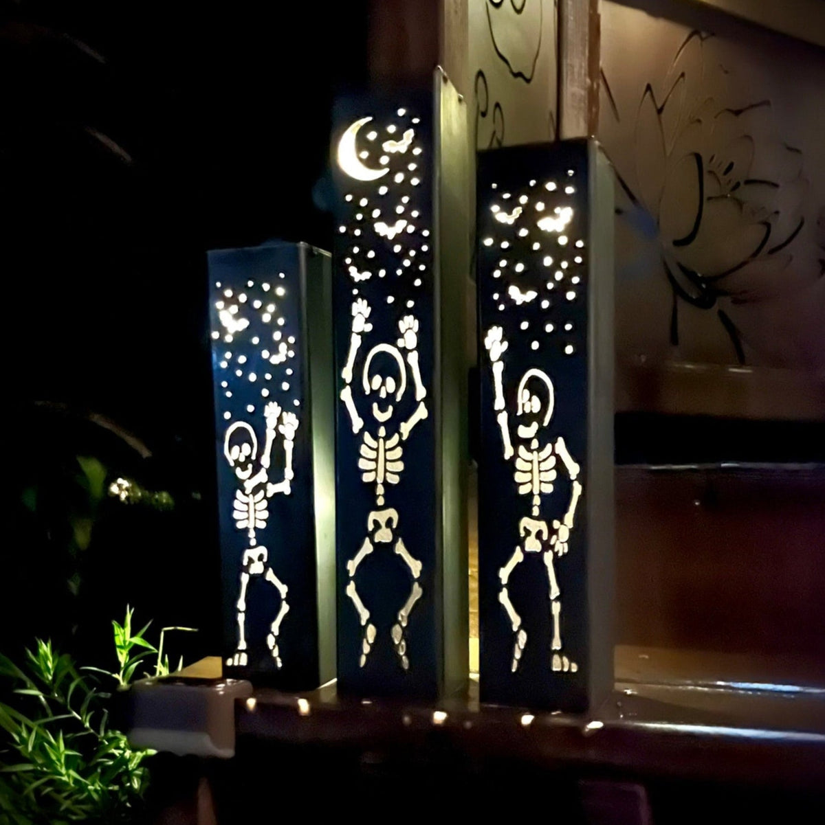 Skeleton solar tube lights with steel posts, dotted face cutouts, warm glow pattern