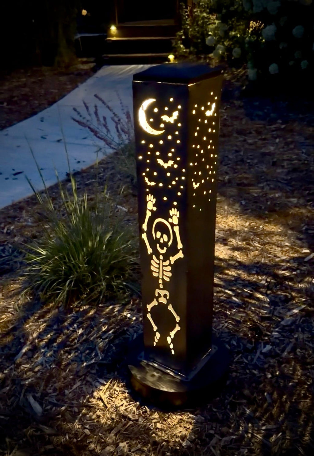 Lit steel solar tube light with skeleton-style cutout pattern in warm light