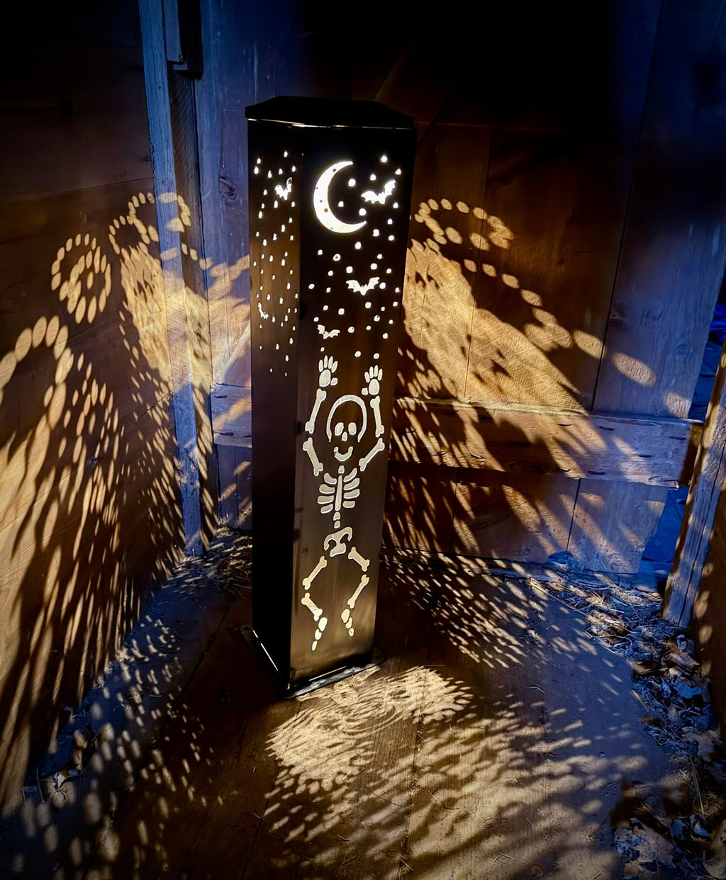 Steel solar tube light with crescent moon and skeleton cutouts casting light through dots