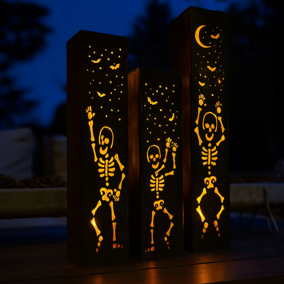 Dark-sky view of steel solar tube lights showing glowing skeleton figures on three posts