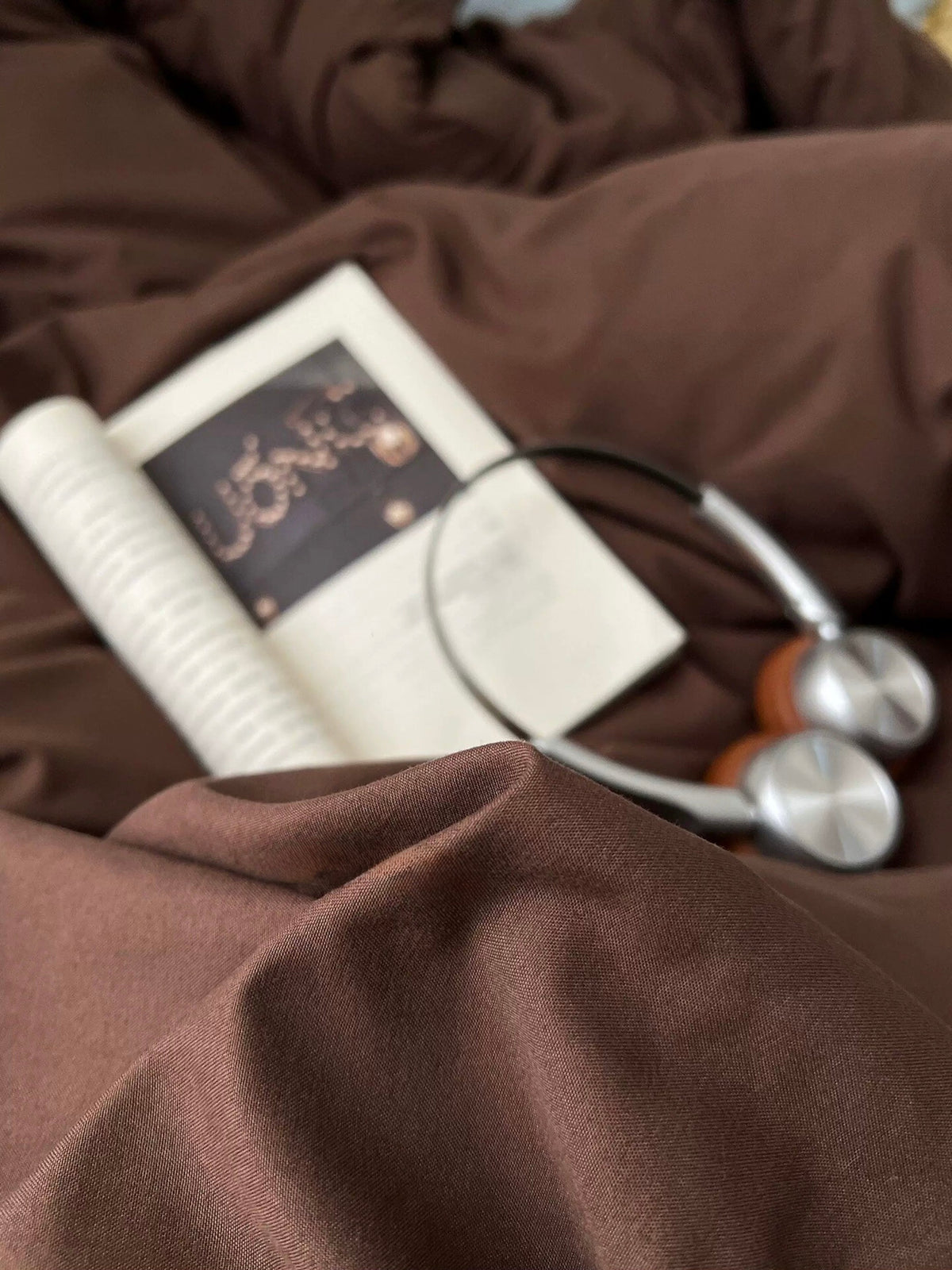 Dark brown bedding close-up with fabric folds and white zipper near corner