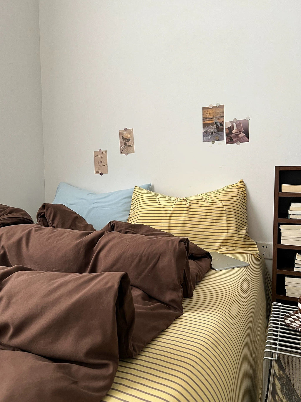 Dark brown comforter with creased folds over bed, paired with striped pillow shams