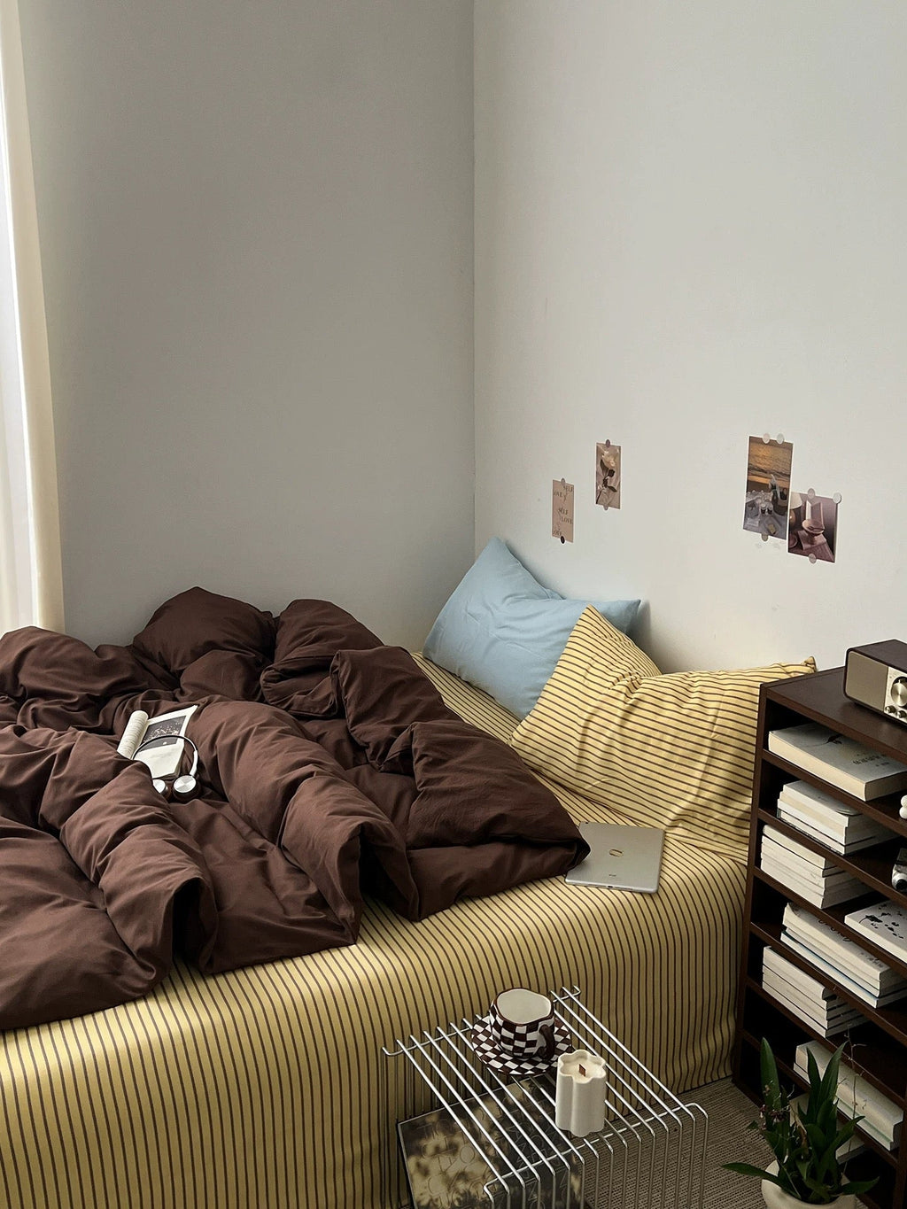Dark brown bedding set draped over bed with blue and yellow striped pillow shams