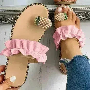 Pink flat slide sandals with pearl pineapple embellishment and ruffled strap