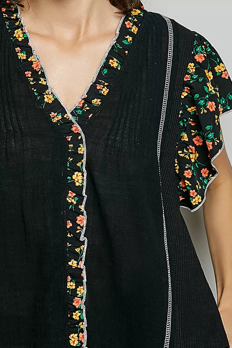 Black V-neck floral ruffle sleeve blouse close-up with embroidered trim and piping