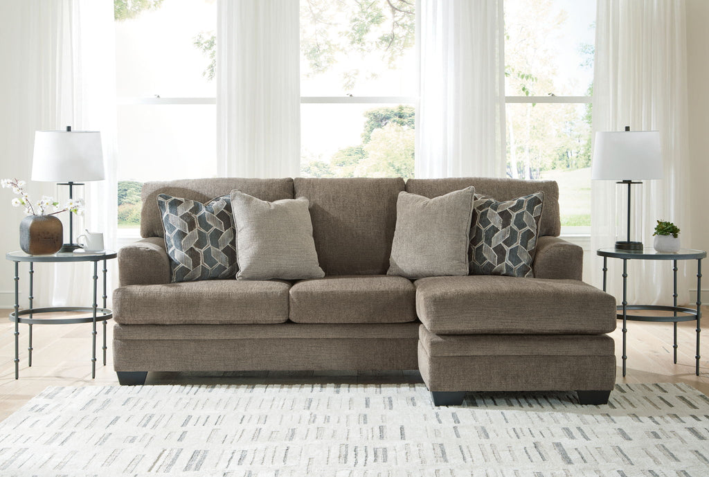 Brown sectional sofa with chaise and multiple throw pillows, upholstered in beige fabric
