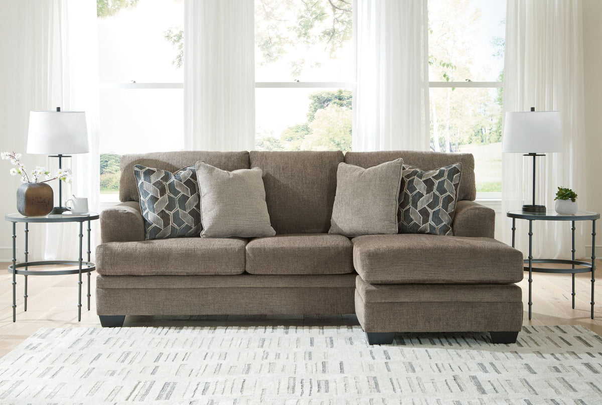 Brown sectional sofa with chaise and multiple throw pillows, upholstered in beige fabric