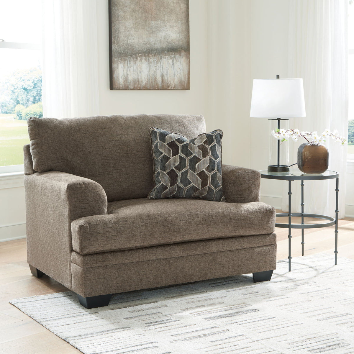 Upholstered armchair in heather gray fabric with two patterned accent pillows and legs