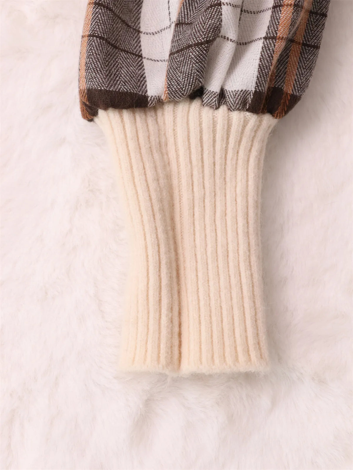 Cream sweater dress hem with ribbed knit skirt and plaid sleeve cuff detail