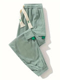 Light green corduroy pants, folded view, with cargo pockets and drawstring ties