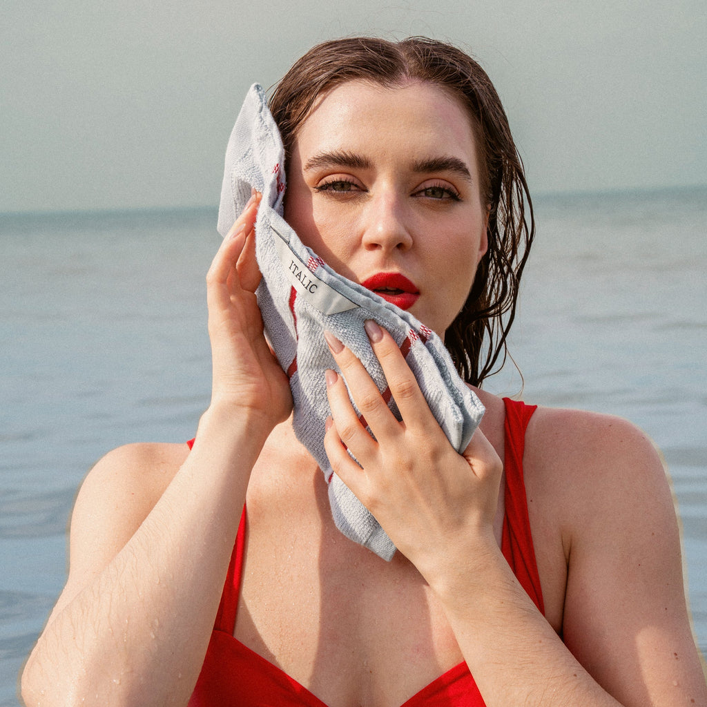 Gray cotton towel with red stripes held in front of the body