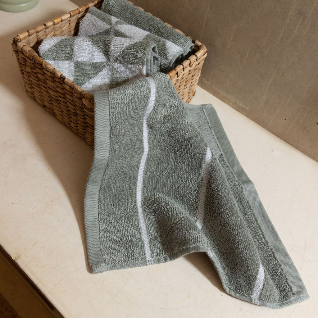 Gray and white geometric cotton towels folded in a wicker basket