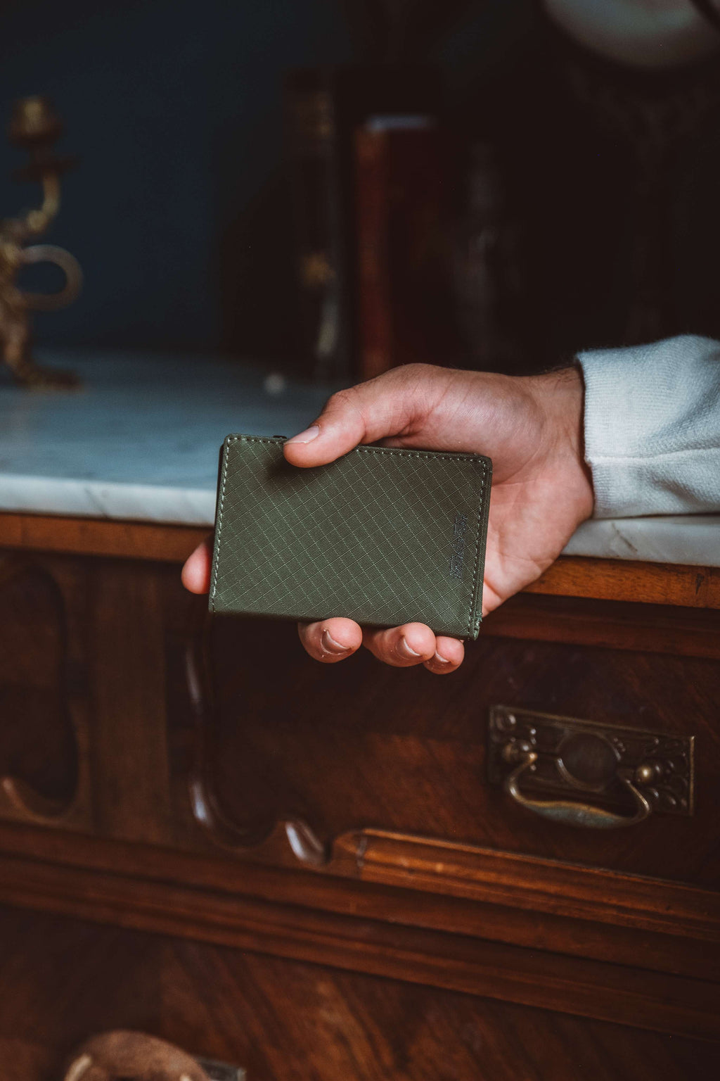 Olive green bifold wallet held in hand with snap front
