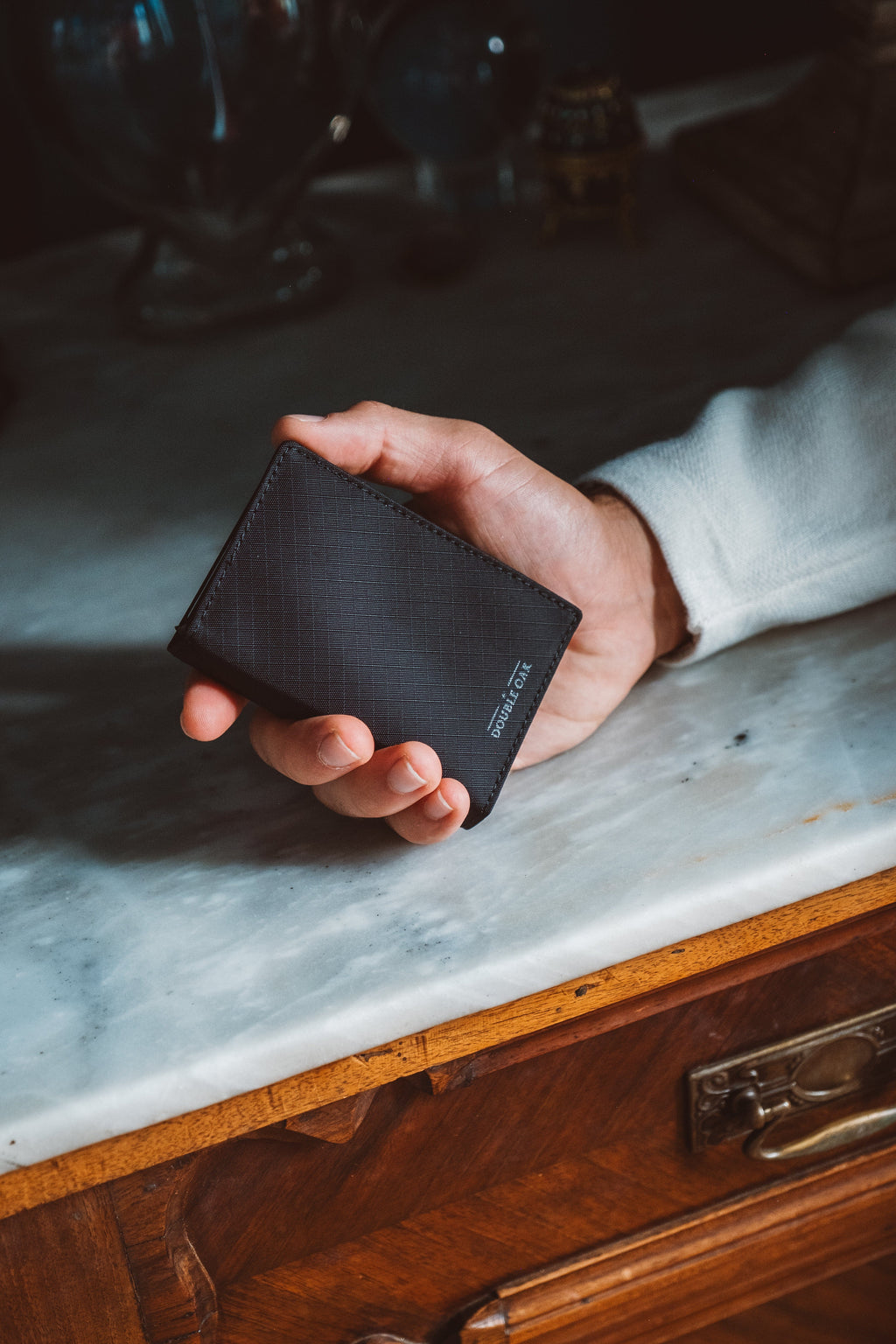 Dark leather bifold wallet held in hand, slim design with snap closure