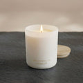 White pillar candle in frosted jar, lit wick, The Roosevelts Candle Co label