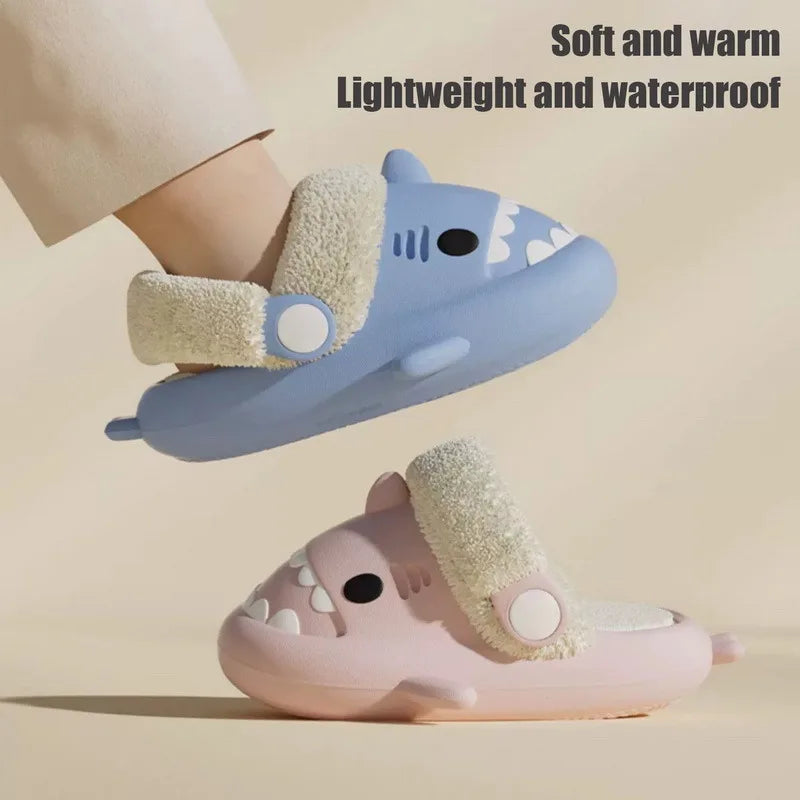 Blue kids shark slippers with plush lining and cuff, shown on a flat surface